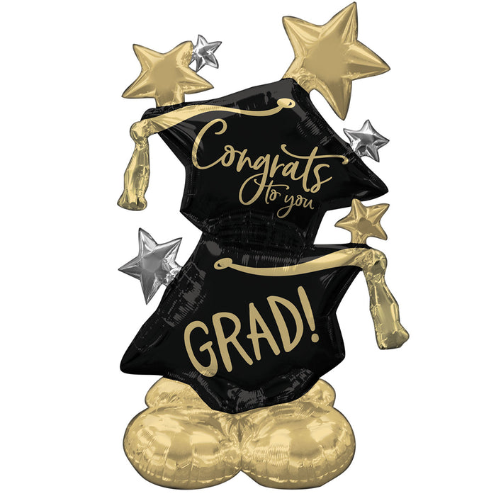 A foil balloon with a graduation cap design, featuring the text 'Congrats to you, GRAD!' and stars in gold and black colors.