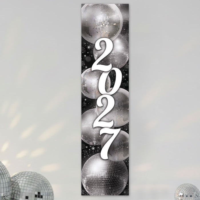 A vertical rectangular wall art print featuring the year '2027' in large white script over a black background with mirrored disco ball illustrations. The print is shown hanging against a light gray wall with decorative disco balls at the bottom corners.