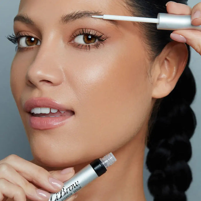 Applying eyebrow serum for fuller, defined brows with precise brush applicator