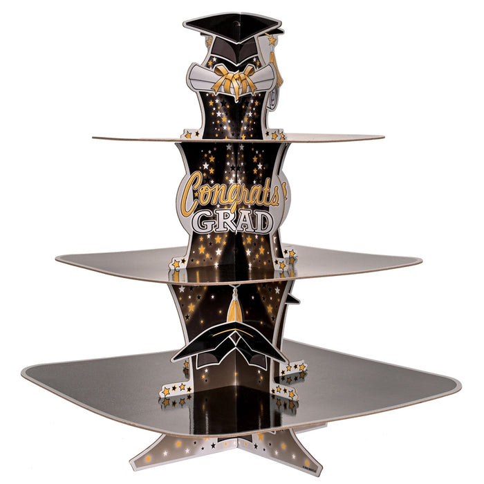 A three-tiered graduation-themed cupcake stand with 'Congrats Grad' text and decorative elements in black, gold, and silver colors.
