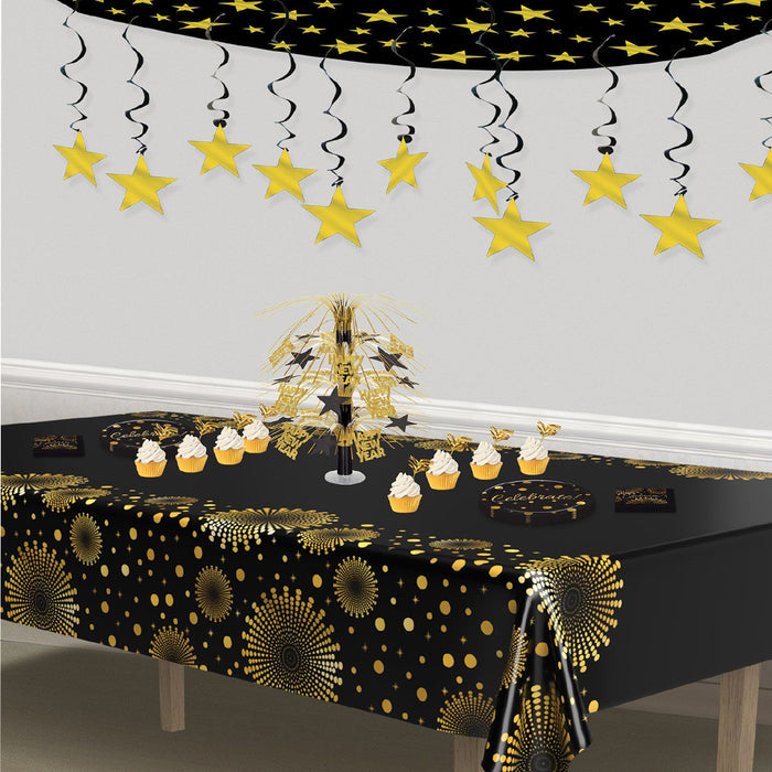 Decorated table with black and gold tablecloth, star-shaped decorations, and small cupcake-like items.
