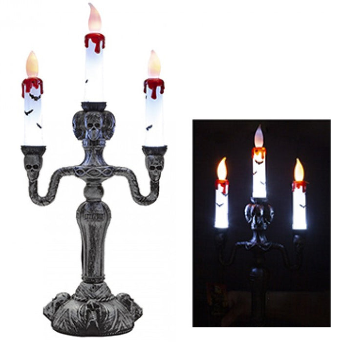 Decorative candle holder with skeleton faces and candles on a white background