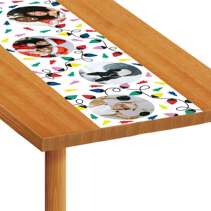 Table runner with Christmas-themed design featuring photos and colorful decorations on a wooden table.
