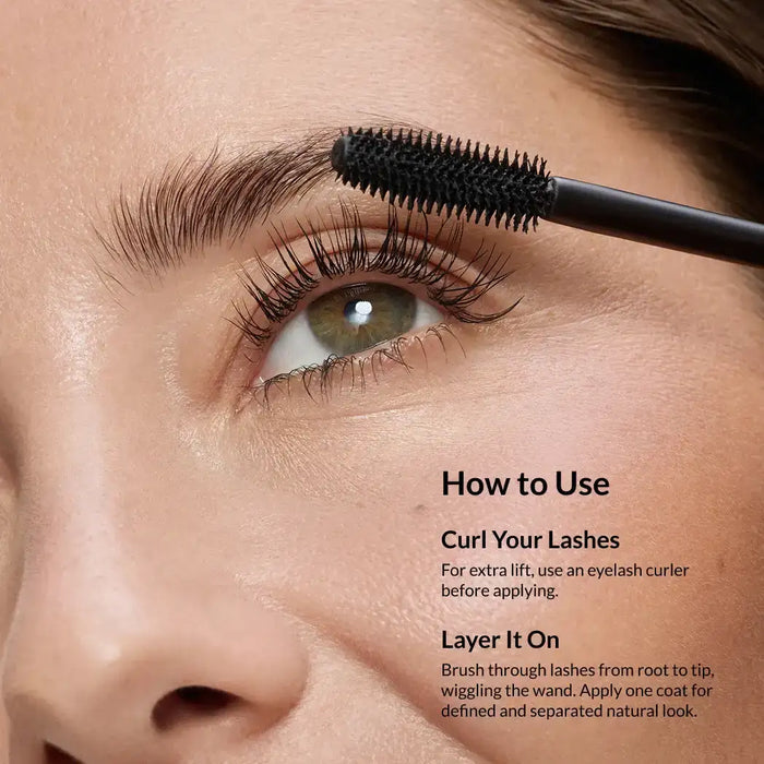 Close-up of a mascara wand applying product to long, defined eyelashes and brows.