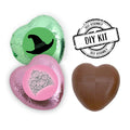 Pack of 24 heart-shaped milk chocolates with pink and green foils, some displaying stickers with witch hat and crown designs, labeled as a 'DIY Kit'.